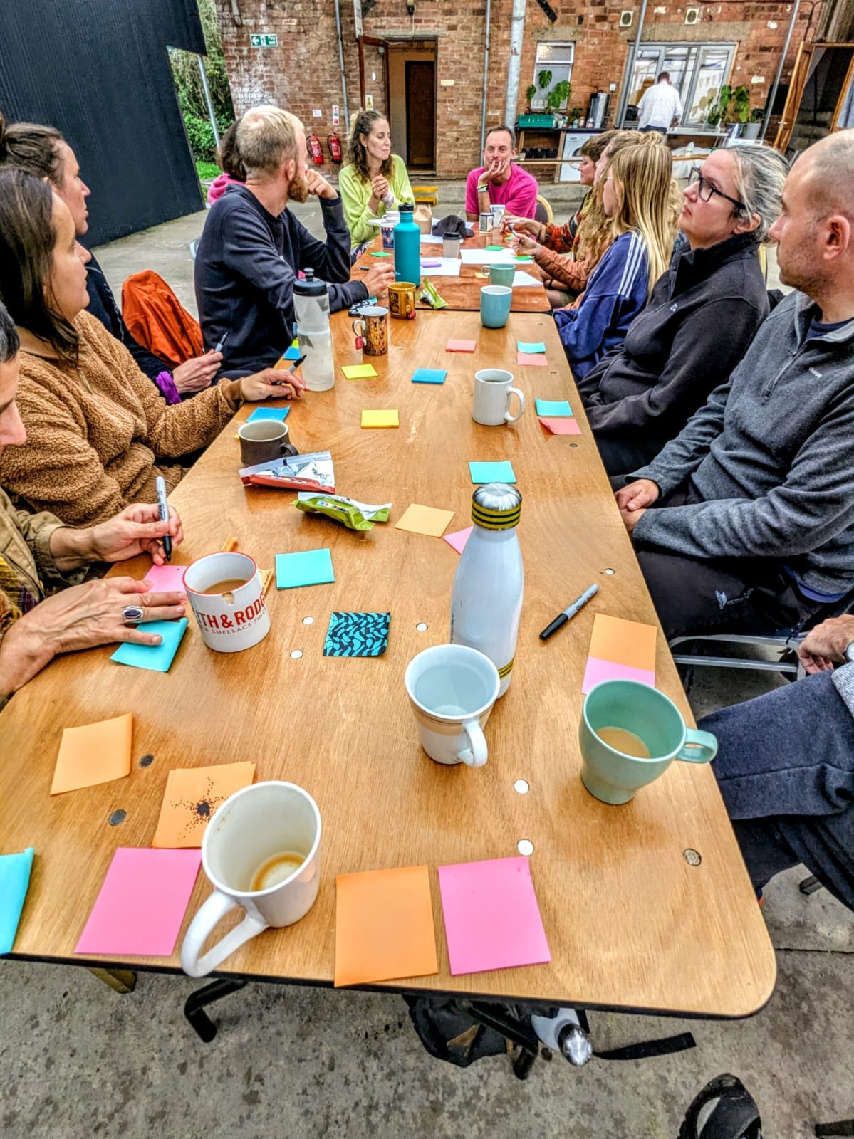 Community meeting around a table with post-it notes and mugs